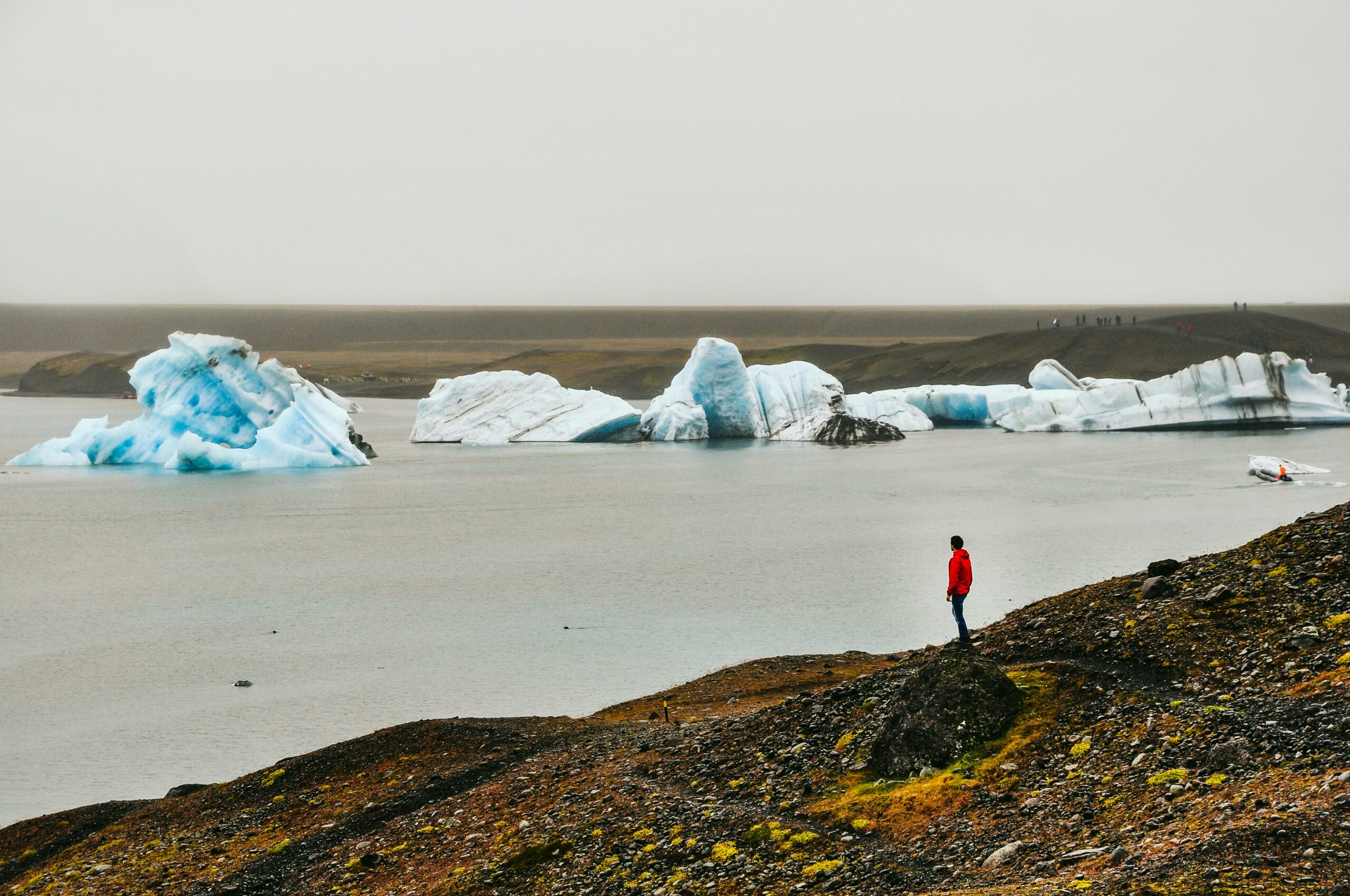 un homme en rouge observe des icebergs dans une baie.